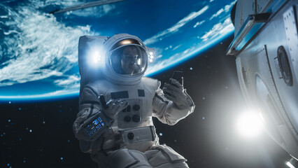 Caucasian Man in a Space Suit Casually Talking on a Mobile Phone in Space While Servicing A Satellite. Astronaut Chatting with Mission Control Crew, Family or Colleagues on a Video Call on Smartphone © Gorodenkoff