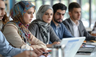 Concentrated diverse businesspeople sit at desk talk brainstorm at office meeting using laptop, focused colleagues consider discuss business ideas