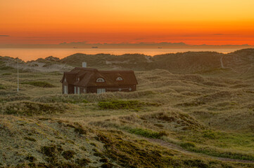 lonely old house in the dunes at sunset