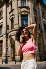 A woman in stylish attire smiles while walking through a European city.