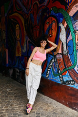 A stylish woman poses against a vibrant graffiti wall during her European travels.