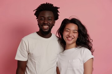 Obraz premium Portrait of a smiling multicultural couple in their 20s dressed in a casual t-shirt isolated on pastel pink background