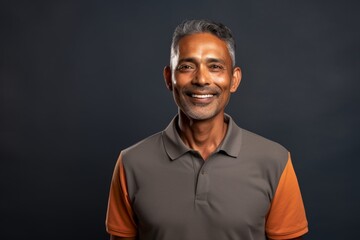 Fototapeta premium Portrait of a cheerful indian man in his 50s wearing a breathable golf polo in blank studio backdrop