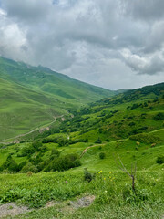 Green meadows and paths against the backdrop of the Caucasus mountains near Vladikavkaz, Russia