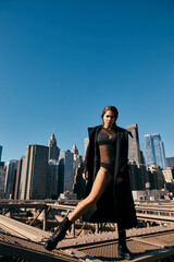 A young woman in black clothing dances on the Brooklyn Bridge in New York City.
