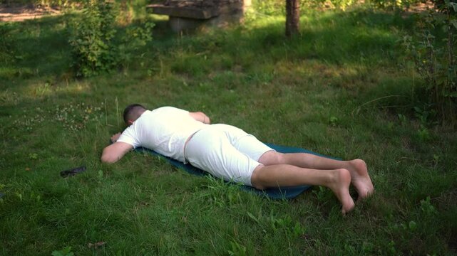  man performs somatic exercises in the garden in the morning