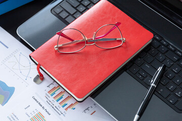 Top view, Office desk with laptop, eyeglass, pen and red notebook