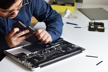 Computer technician wearing glasses, laptop motherboard repairer, using his hands to remove old battery from computer, illustration of computer technician work
