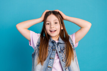 Fototapeta premium Photo portrait of charming little girl touch head amazed reaction wear trendy jeans outfit isolated on blue color background