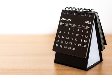 January 2025 black calendar - month page on the wooden desk