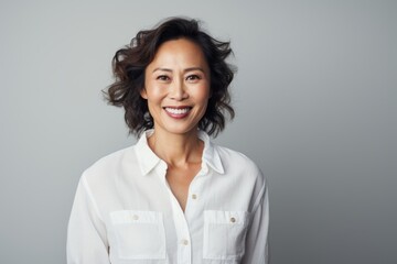 Portrait of a grinning asian woman in her 50s wearing a simple cotton shirt in plain white digital canvas
