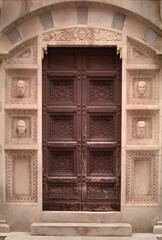 Brown door of a church with some heads decoration