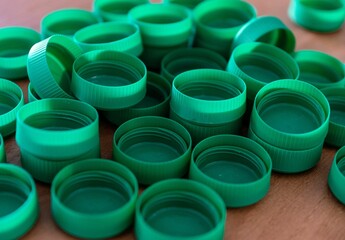 Close-up of multiple green plastic bottle caps scattered on a wooden surface