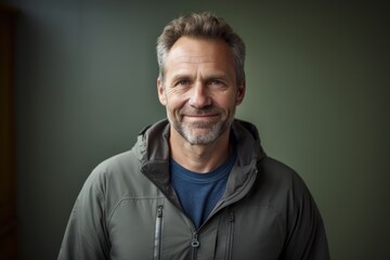 Obraz premium Portrait of a satisfied man in his 50s sporting a breathable hiking shirt on bare monochromatic room