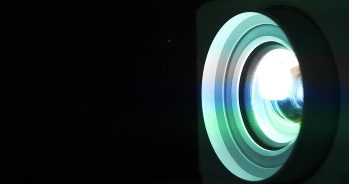 Cinema hall. Projector lens in operation. Movie is shown through projector. Light of different colors passes through lenses