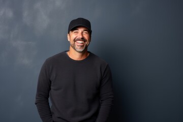 Portrait of a happy man in his 40s sporting a trendy beanie while standing against plain cyclorama studio wall