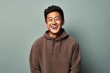 Obraz premium Portrait of a happy asian man in his 20s wearing a thermal fleece pullover on plain cyclorama studio wall