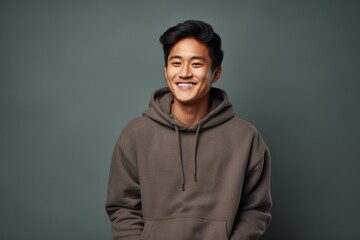 Portrait of a happy asian man in his 20s wearing a thermal fleece pullover while standing against plain cyclorama studio wall