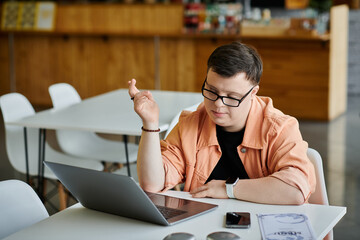 A man with Down syndrome works remotely on a laptop in a cafe.