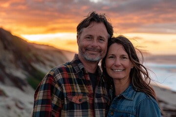 Fototapeta premium Portrait of a satisfied caucasian couple in their 30s wearing a comfy flannel shirt while standing against stunning sunset beach background
