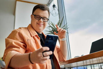A man with Down syndrome works remotely on his phone in a cafe, smiling and enjoying his work.