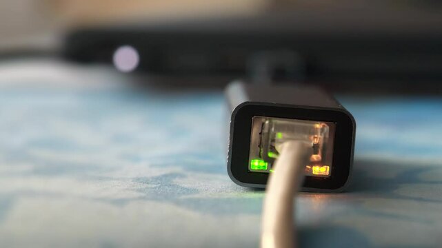 Ethernet cable adapter. Working ethernet cable adapter with green LED and flashing yellow LED. Internet cable through an adapter connected to laptop