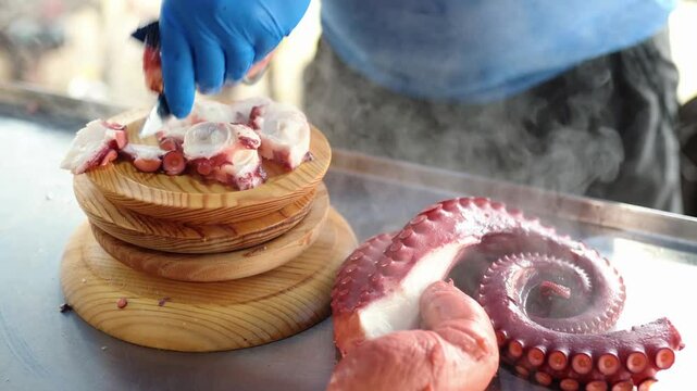 unrecognizable professional person cutting the tentacles of a cooked octopus into small slices to prepare a tapa of Galician octopus. Traditional Spanish food.