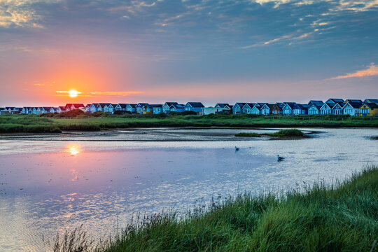 Sunrise at Mudeford Sandspit Lagoon with the beach huts on Mudeford Spit in the distance, Dorset, England