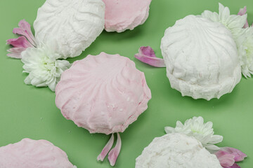 Fruit marshmallow with fresh flower petals on pastel green background. Lactose free vegan dessert