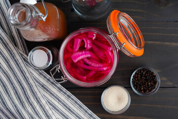 Jar of Pickled Onions Viewed from Directly Above: Brightly colored sliced red onion pickled in a mason jar surrounded with ingredients