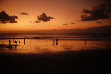 Kuta, Bali, Indonesia - July 12, 2024 : Silhouette view of the sunset reflection on the beach