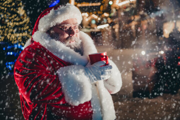 Photo of cool man santa claus travel holiday street spend weekend hold mug full delicious aromatic beverage cacao enjoy miracle outside