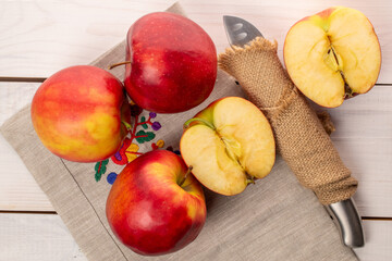 Several red apples with knife and napkin on wooden table, macro, top view.