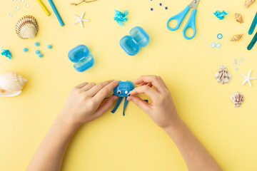 Adorable jellyfish made from plastic blue egg, Kids craft at home or kindergarten. Hands making DIY summer crafting with children. Ocean's day.