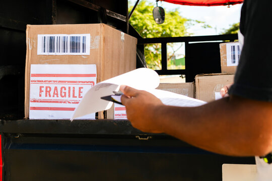 Close-up of a box labeled "Fragile" inside the cargo area of a three-wheeled vehicle. Several other boxes are visible, ready for delivery