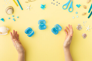 Adorable jellyfish made from plastic blue egg, Kids craft at home or kindergarten. Hands making DIY summer crafting with children. Ocean's day.