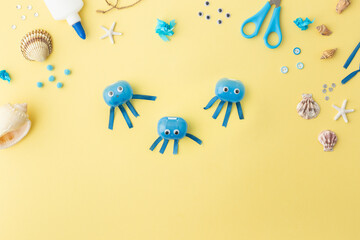 Adorable jellyfish made from plastic blue egg, Kids craft at home or kindergarten. Hands making DIY summer crafting with children. Ocean's day.