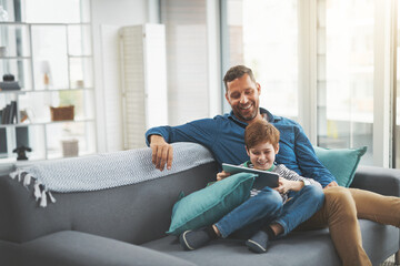 Man, smile and son with tablet on sofa for online gaming, entertainment and streaming together. Family, home and child with tech by father for network, connection or bonding on weekend in living room