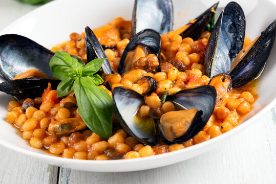 Piatto di fregula con salsa di cozze, tipica pasta sarda, cibo italiano, gastronomia mediterranea 