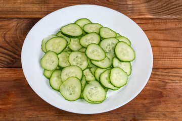 Fresh cucumbers cut into circles on dish on rustic table