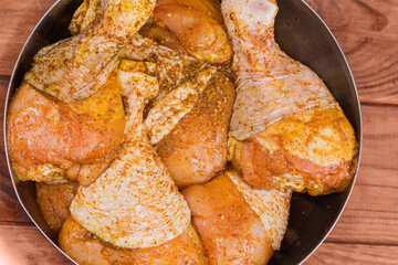 Raw chicken drumsticks with spices in metal bowl, top view