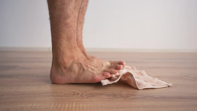 Close-up of Male Legs Doing Special Exercises with a Towel to Treat Flat Feet. Concept of Therapeutic Physical Culture. Foot Health.