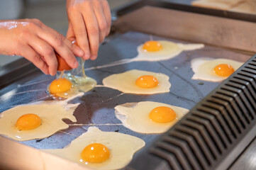 Cocinado de huevos a la plancha. Mano de una mujer mientras cocina los huevos. 