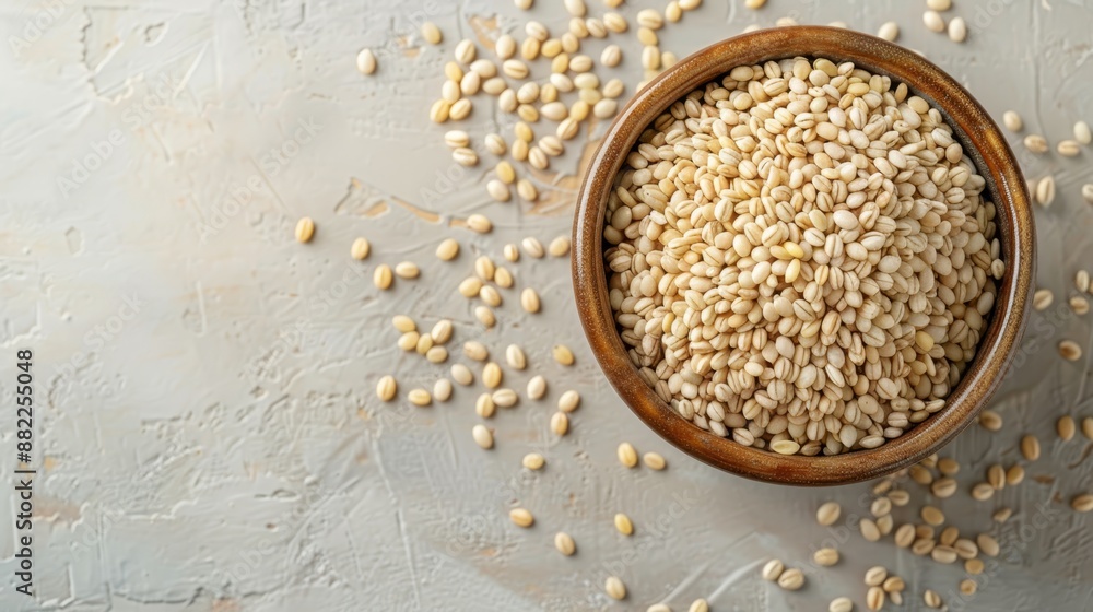 Poster  A wooden bowl brimming with sesame seeds sits atop a white and gray counter, beside a mound of additional seeds