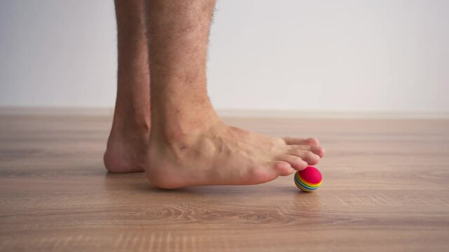 Close-up of Male Legs Doing Special Exercises with a Ball to Treat Flat Feet. Concept of Therapeutic Physical Culture. Foot Health.