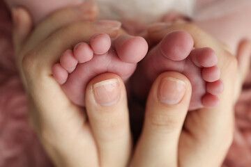 Mother is doing massage on her baby foot. Closeup baby feet in mother hands. Prevention of flat feet, development, muscle tone, dysplasia. Family, love, care, and health concepts. Studio macro. 