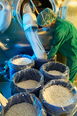 Worker filling drums with white pills