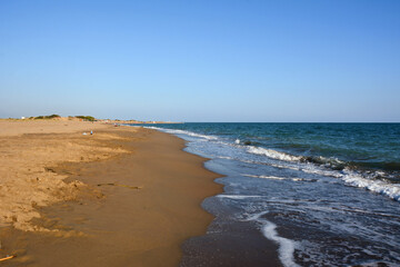 A sandy sea beach in perspective under a clear blue sky. Summer tourist landscape