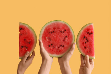 Female hands with half and slices of ripe watermelon on yellow background
