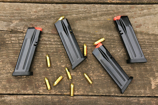 Modern automatic pistol magazines and 9mm ammunition on the background of old boards.